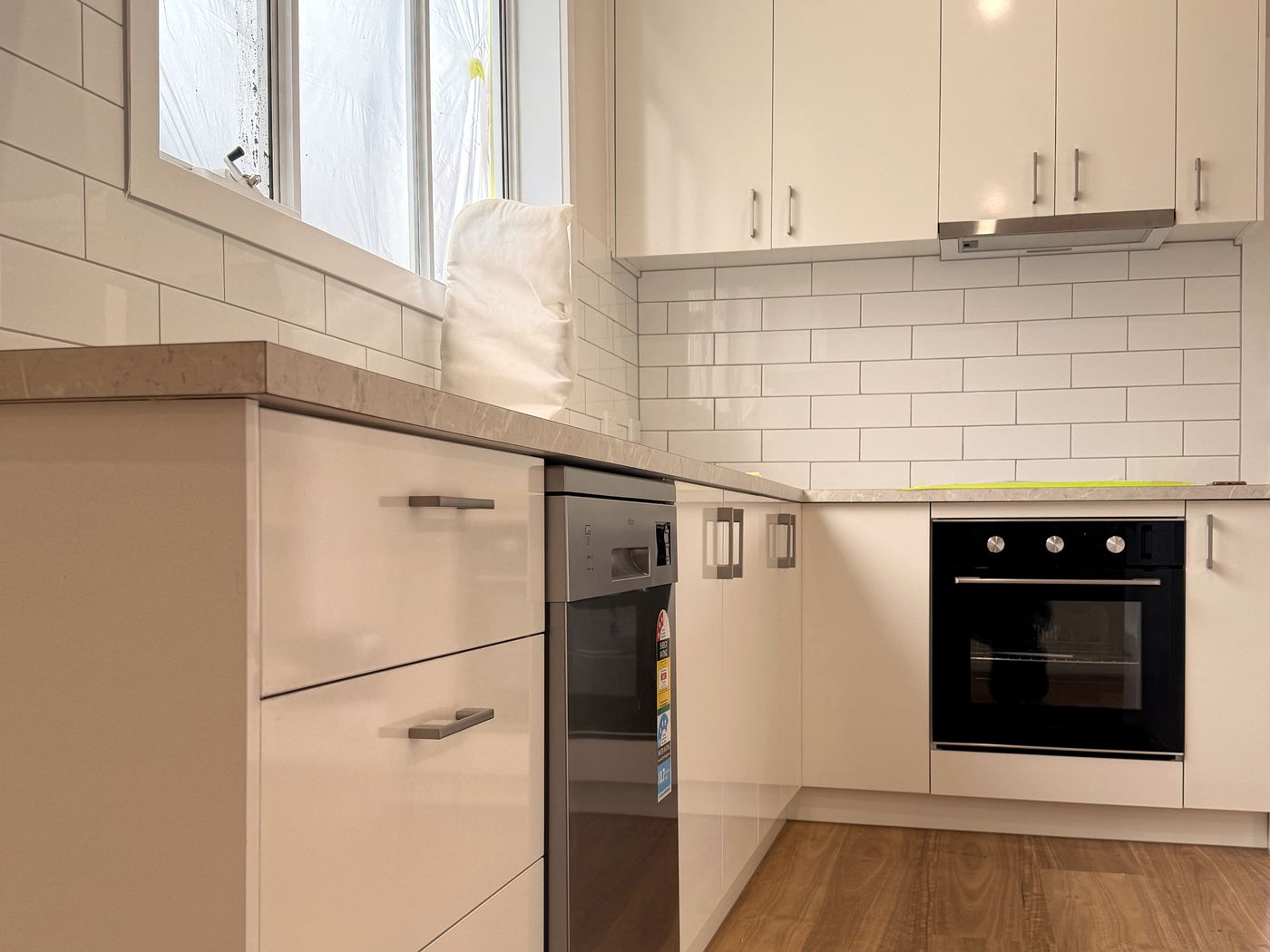 Completed kitchen with white cabinetry, tiled splashback and appliances by JT Handyman Solutionz